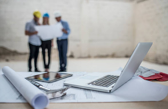 Construction workspace with blueprints and laptop